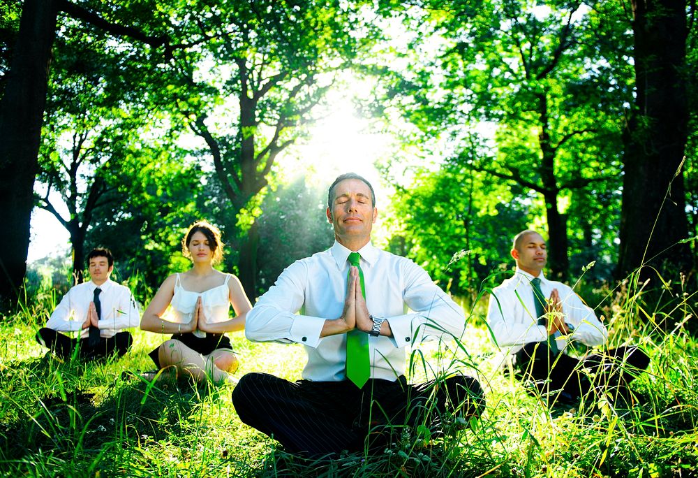 Business people meditating in the woods.