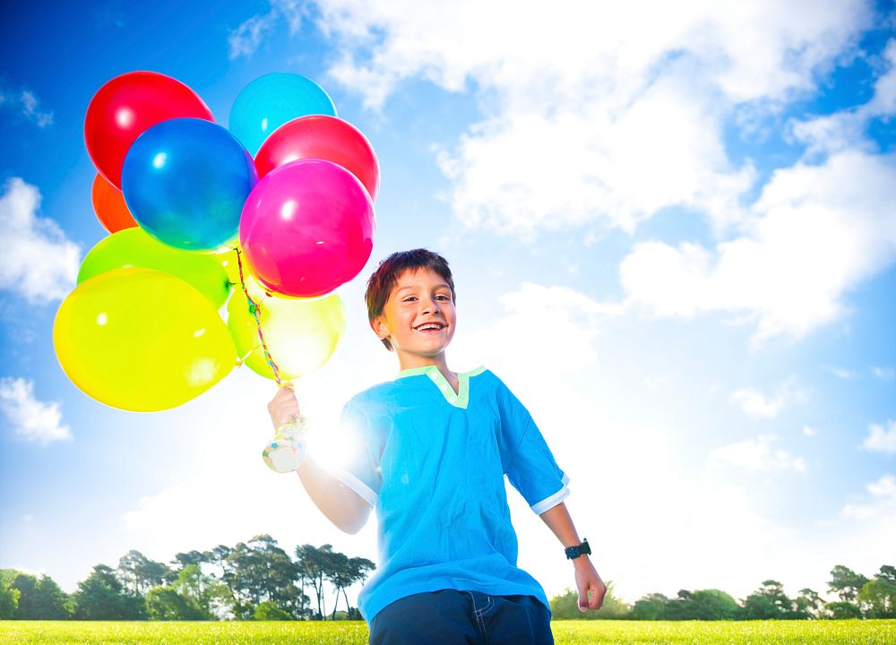 Happy boy outdoors with a dozen of helium balloons.