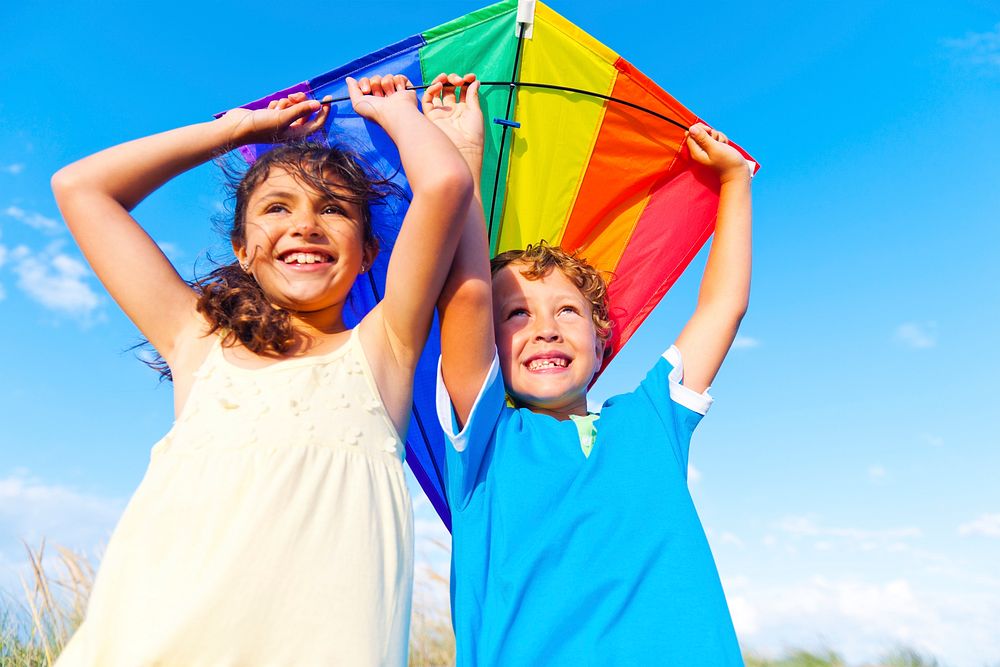 Little girl and little boy playing kite together.