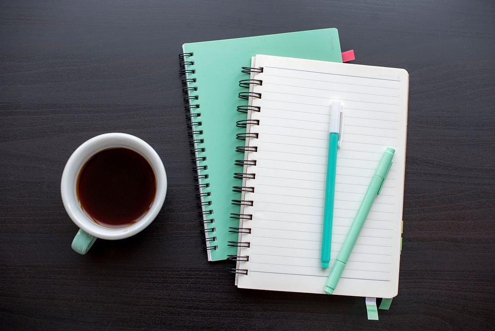 Mint green open notebook and a cup of coffee