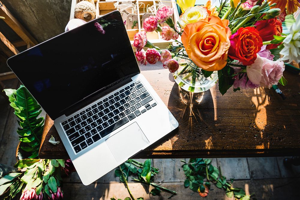 Laptop on workspace with flower decoration