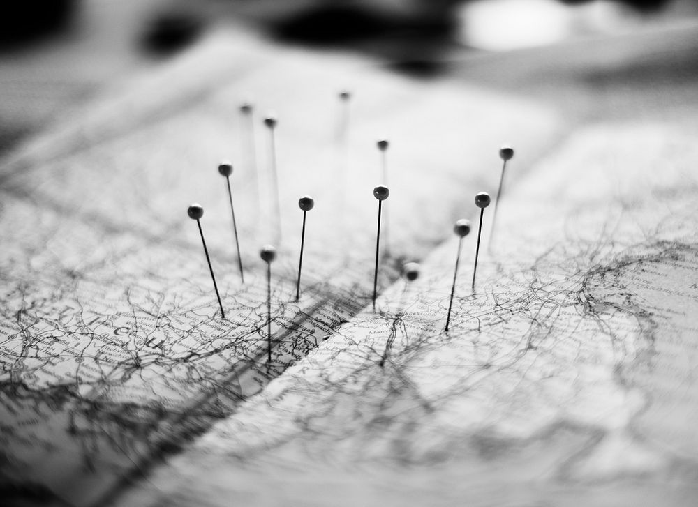 Closeup of pins on the map planning travel journey grayscale