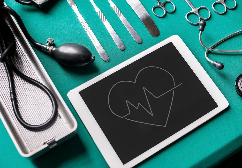 Heart rate icon on a tablet and medical tools on the table