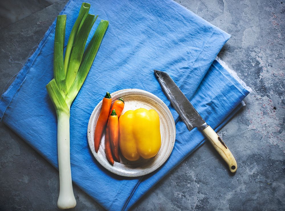 Scallions chili bell pepper knife and a blue fabric