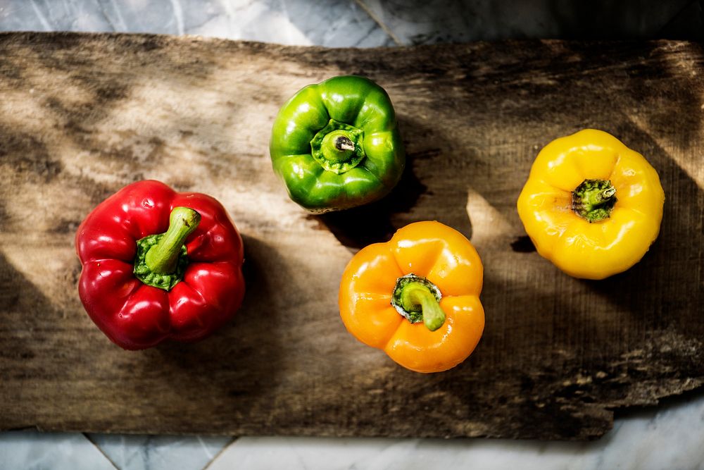Different color bell pepper on a wooden board