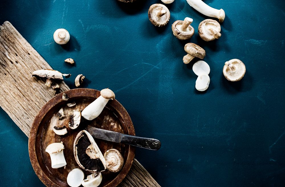 Raw mushroom with knife and wooden plate