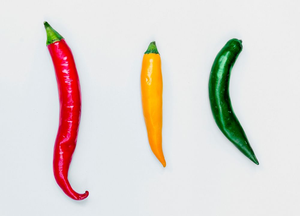 Aerial view of fresh red green yellow chili peppers on white background