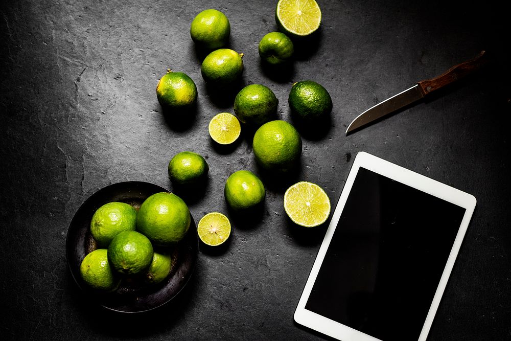 Limes with knife on black background