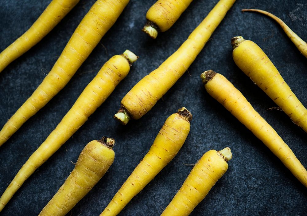 Closeup of yellow fresh organic carrots on black background