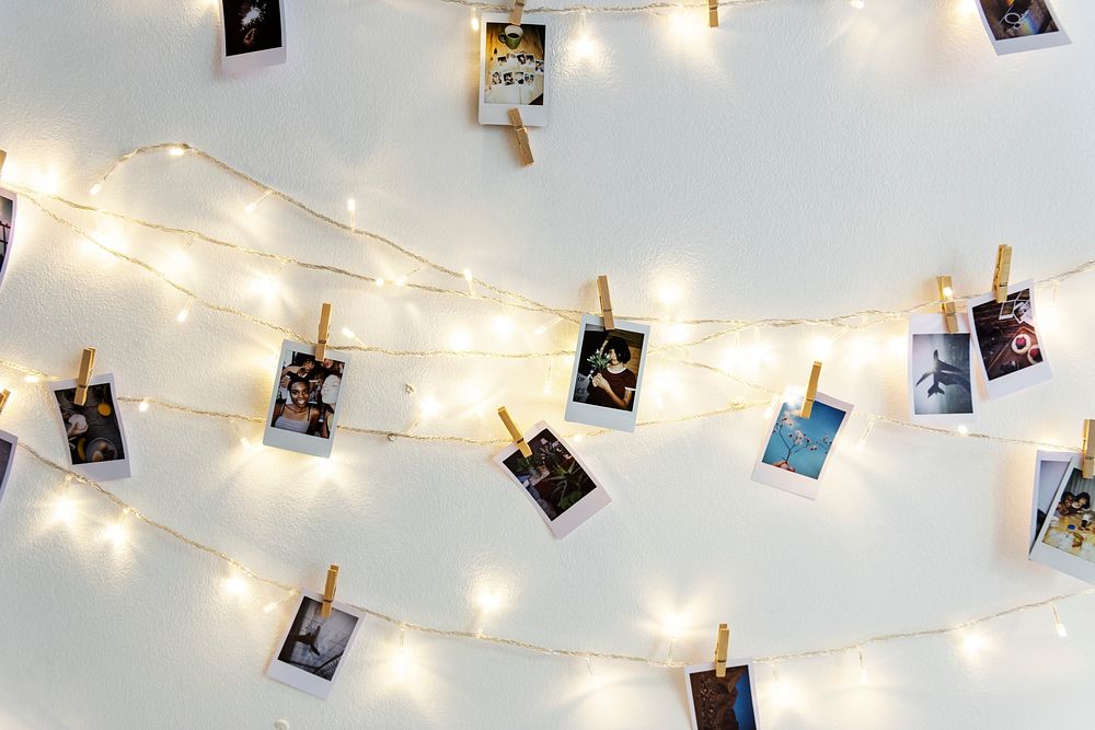 Photos hanging with decoration lights on the white wall