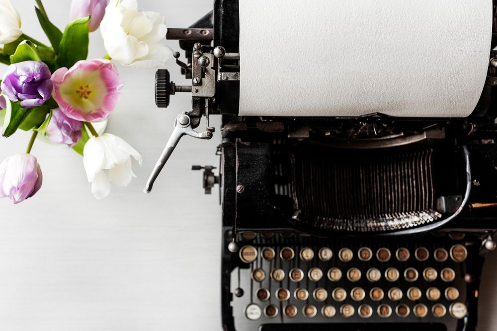 Retro Typewriter Machine with Paper by Flowers in Vase