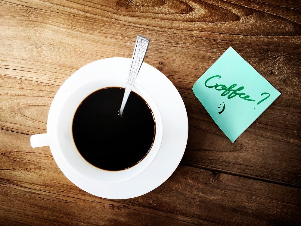 Aerial view of coffee cup on wooden table with sticky note