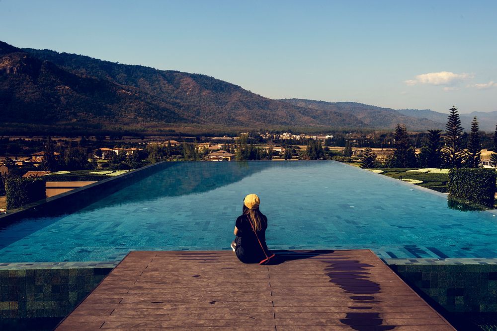Woman Sitting by Poolside wiht Mountain View