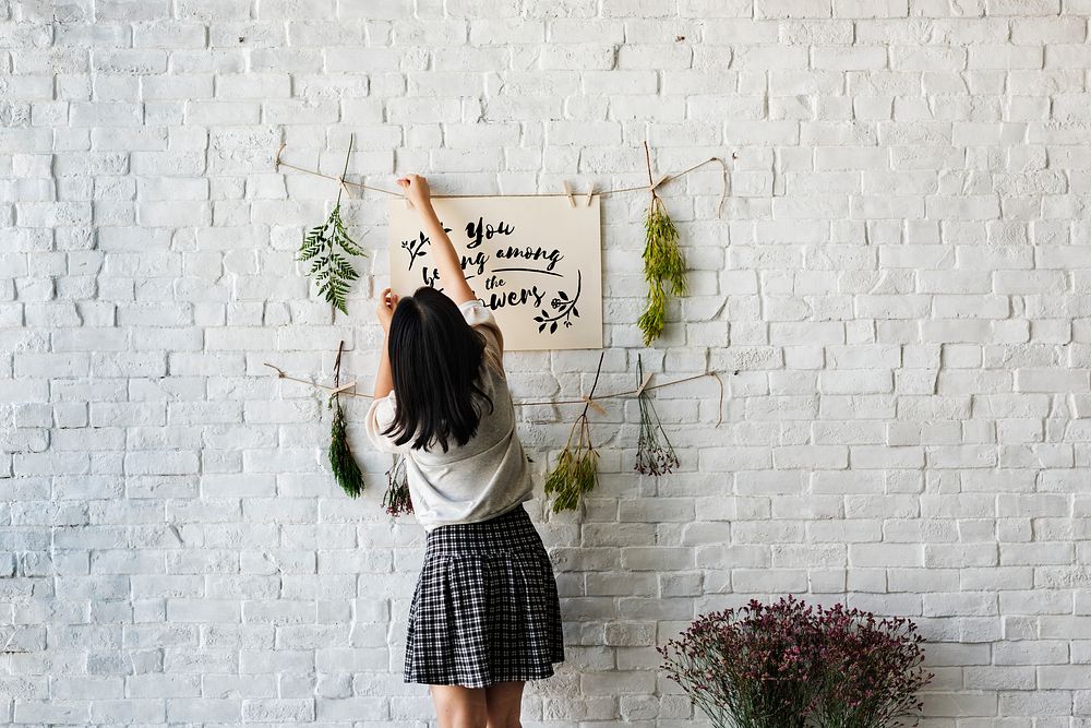 A woman decorating the wall with flowers