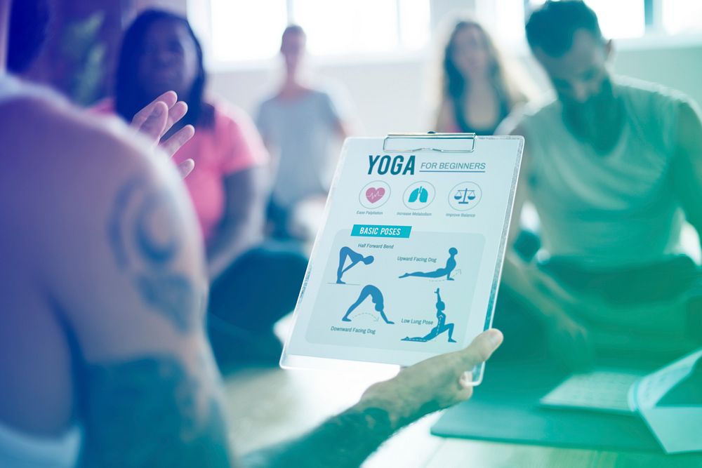 Close up of yoga position on clipboard with a class in the background