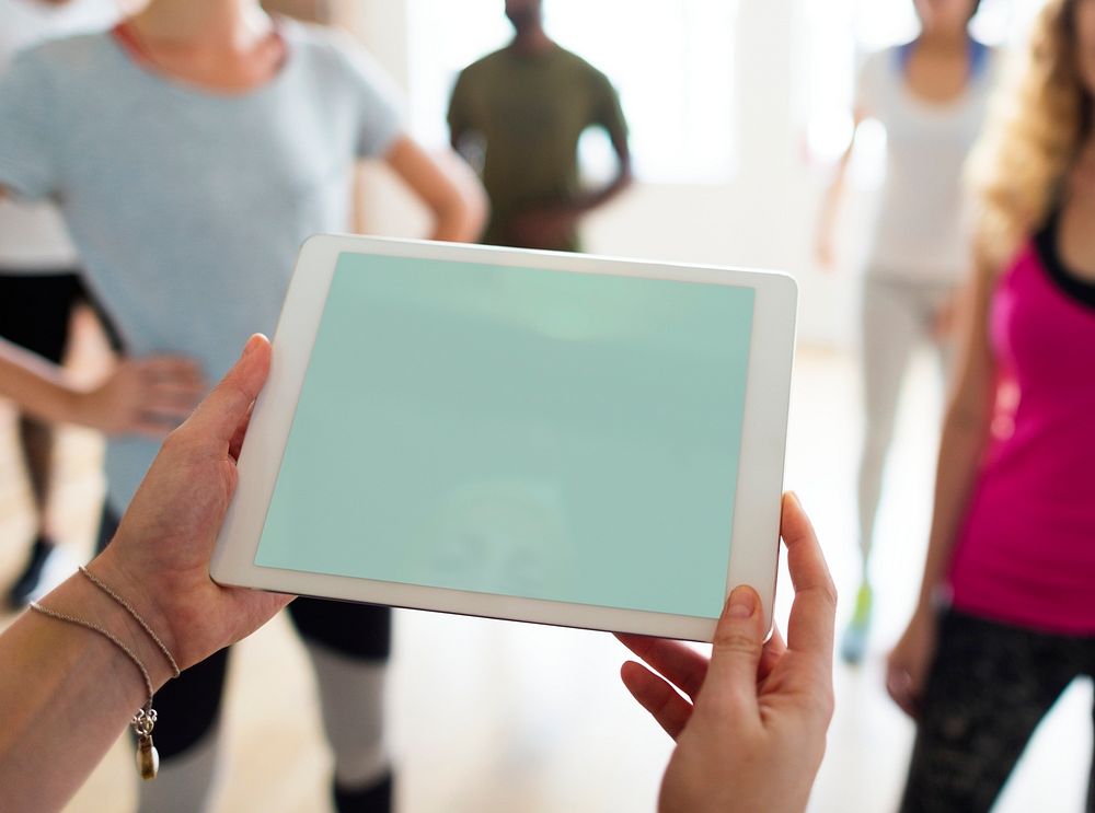 Closeup of a tablet copyspace and diverse people in an exercise class as a background