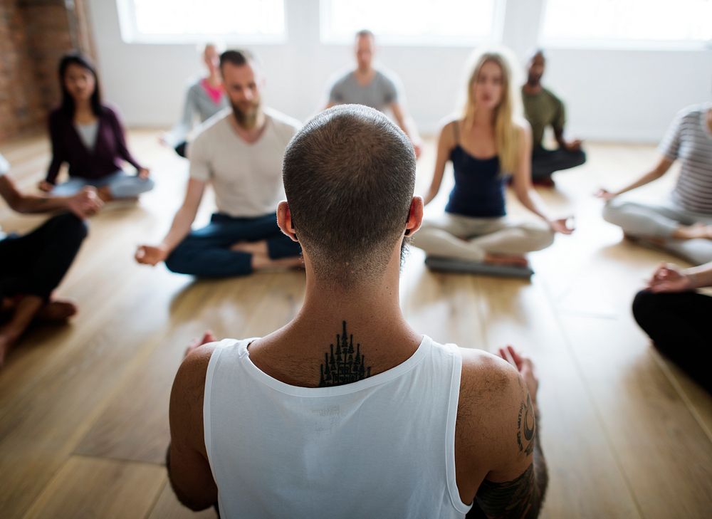 Diverse group of people in a yoga class doing a meditating pose