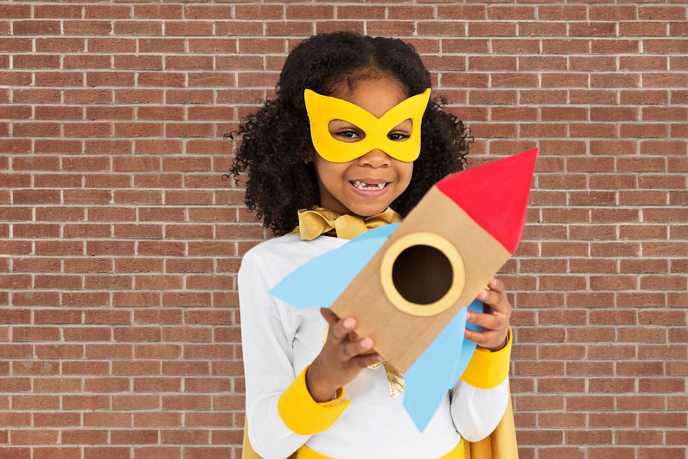 Curly haired cute superhero girl holding a rocket shaped paper prop
