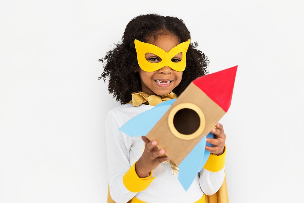 Curly haired cute superhero girl holding a rocket shaped paper prop