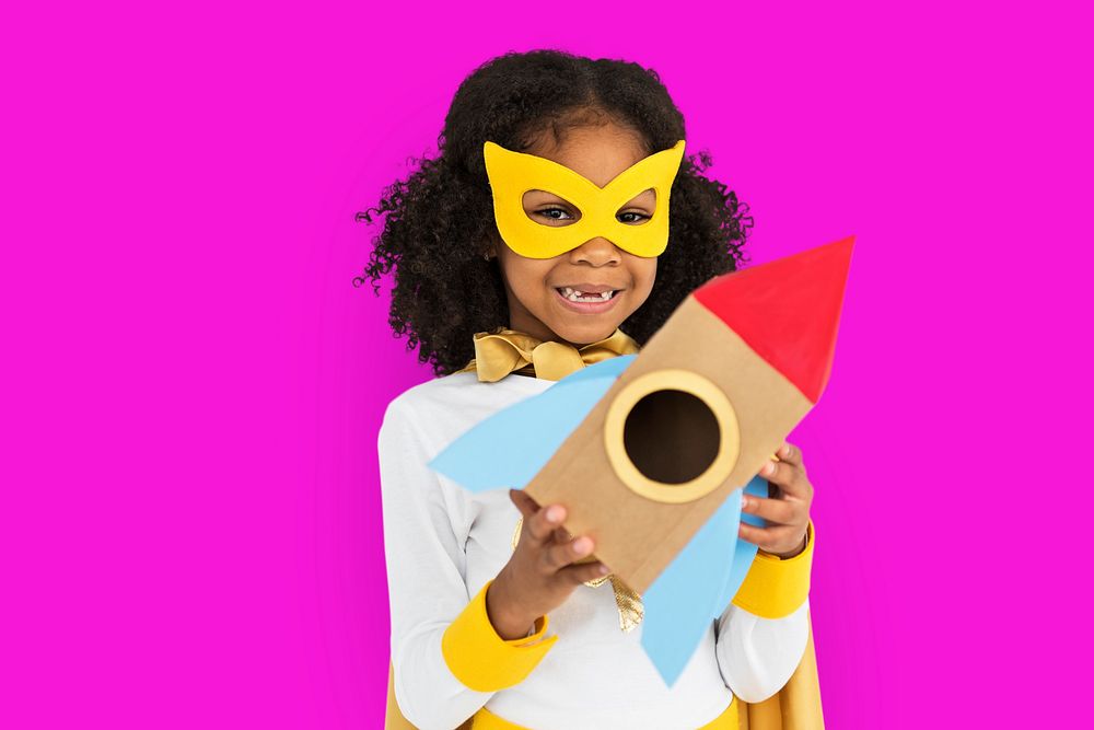 Curly haired cute superhero girl holding a rocket shaped paper prop