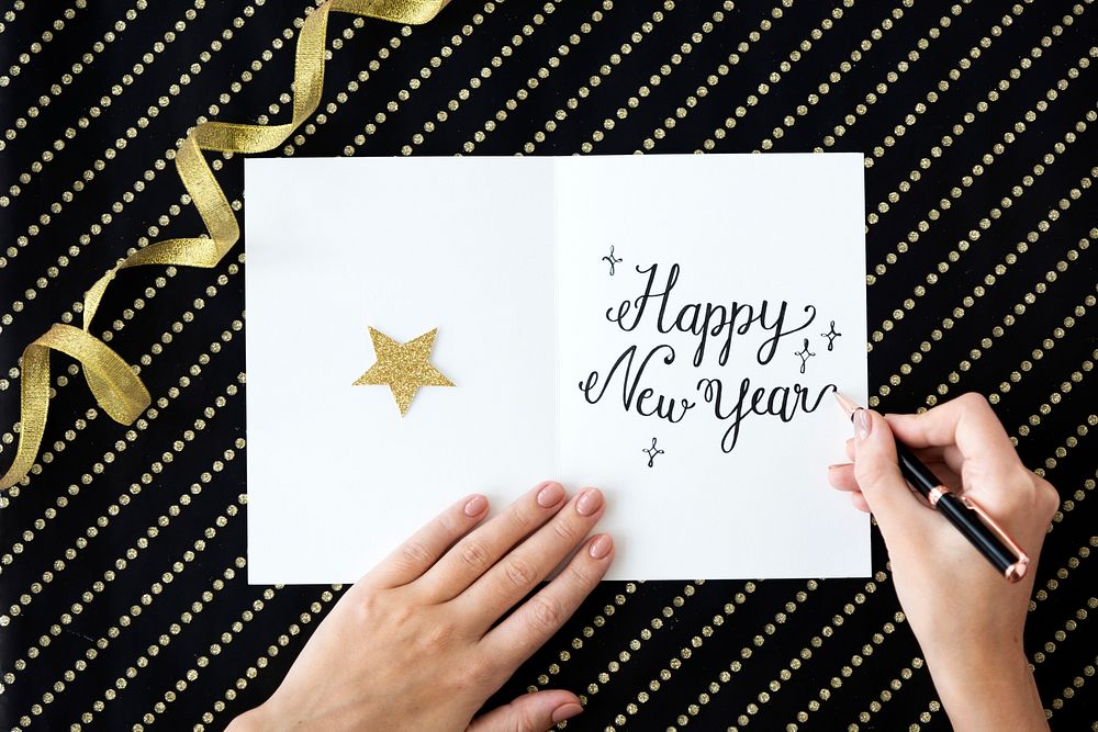 Aerial view closeup of hand writing new year wish on card