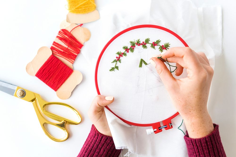 Hands making holly berries embroidery