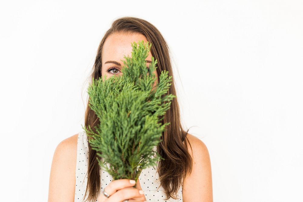 Girl holding pine leaves hiding her face
