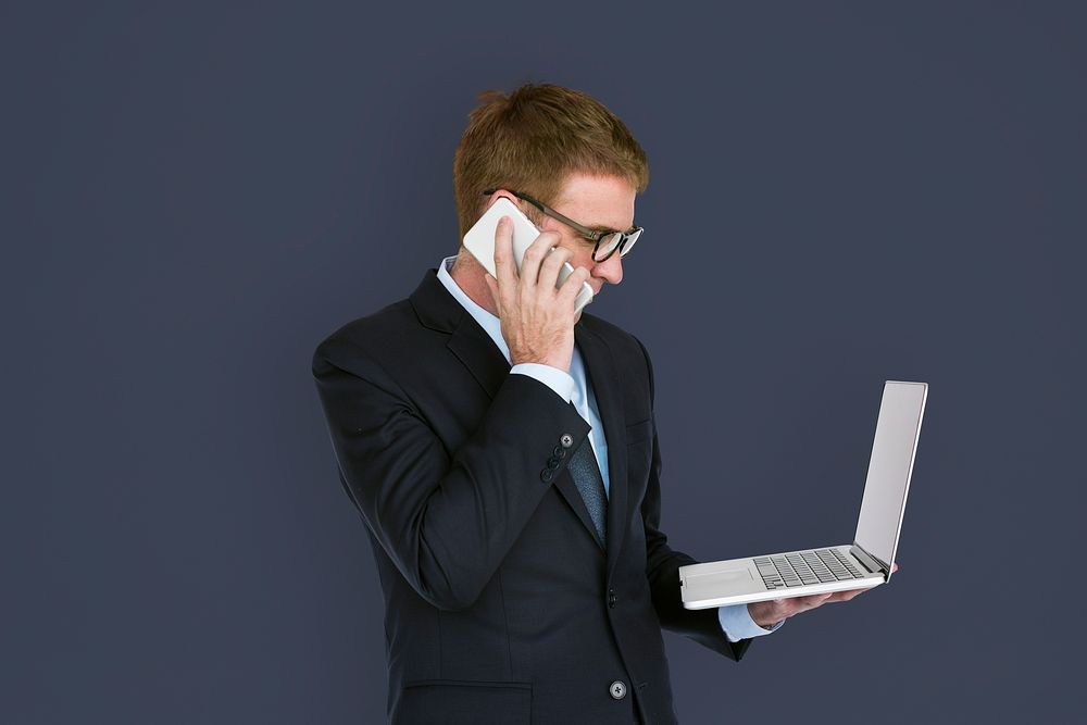 Business man holding a laptop and using his phone