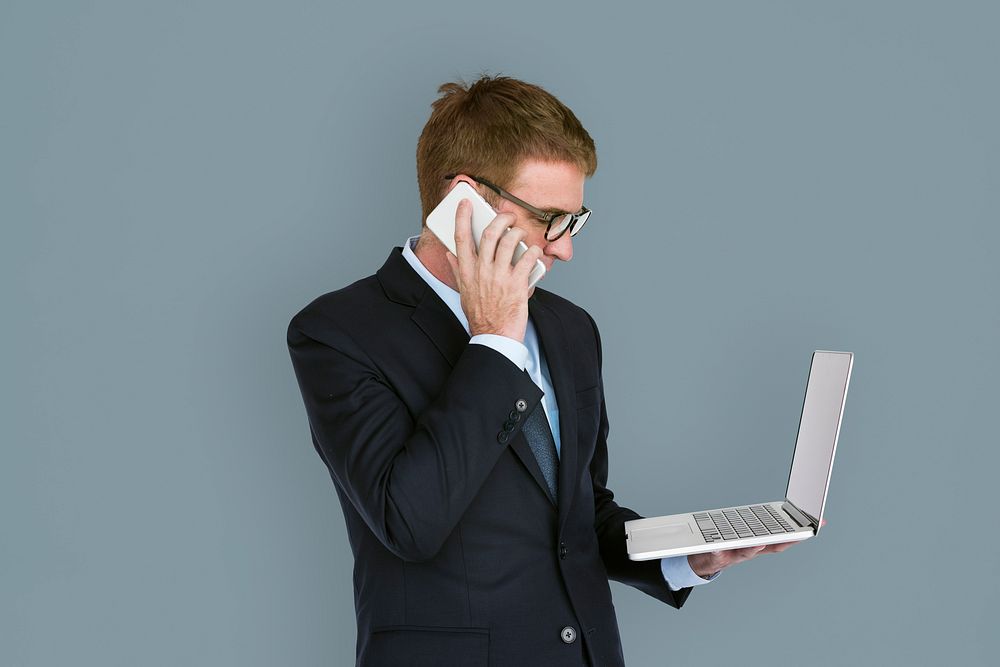 Business man holding a laptop and using his phone