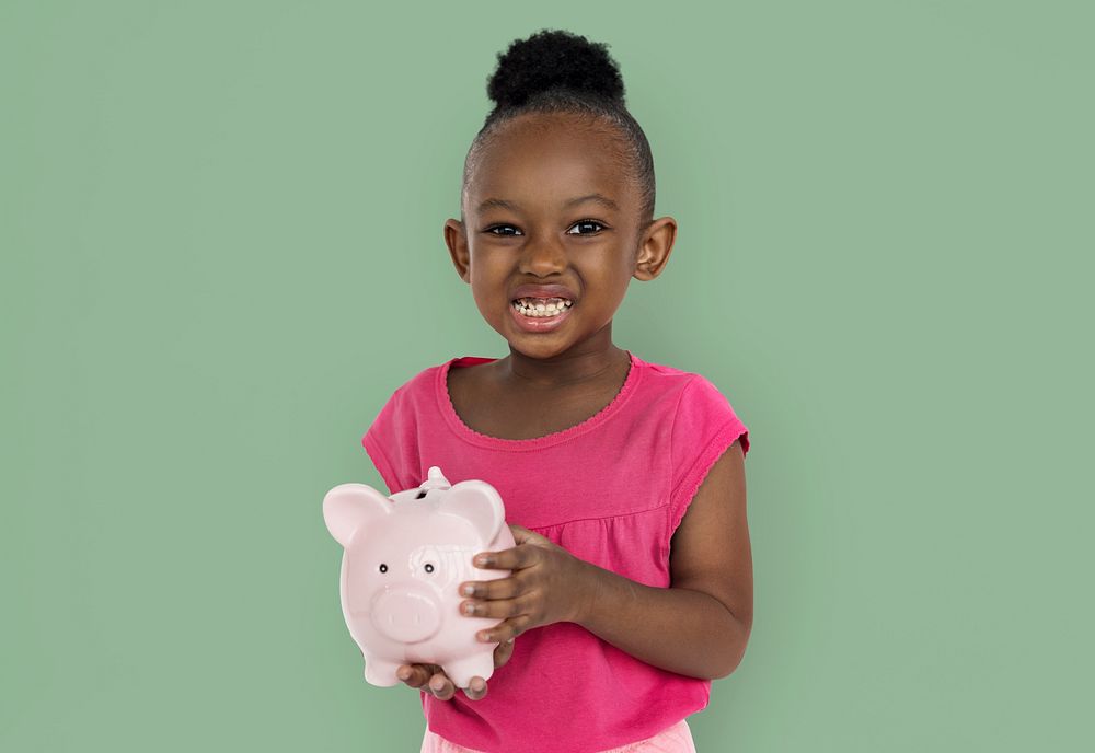 Cute little girl smiling awkwardly holding a piggy bank