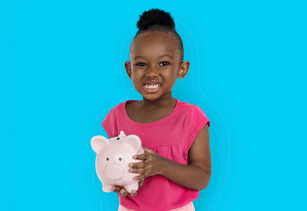 Cute little girl smiling awkwardly holding a piggy bank