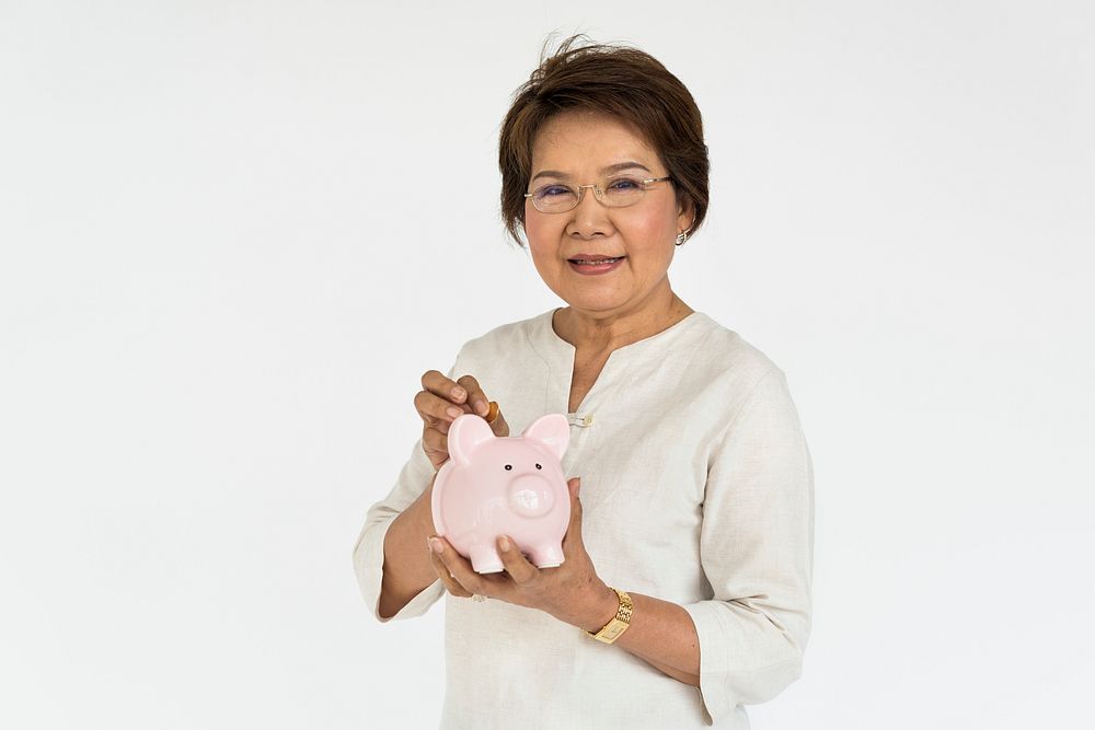 Studio portrait of a senior lady with a piggy bank