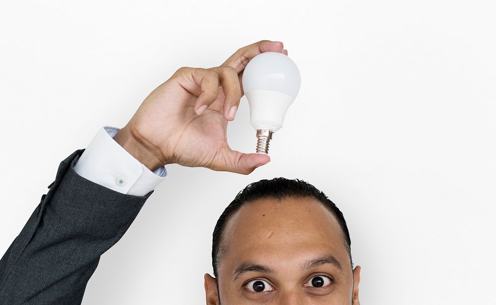 Studio portrait of a guy holding a light bulb on top of his head