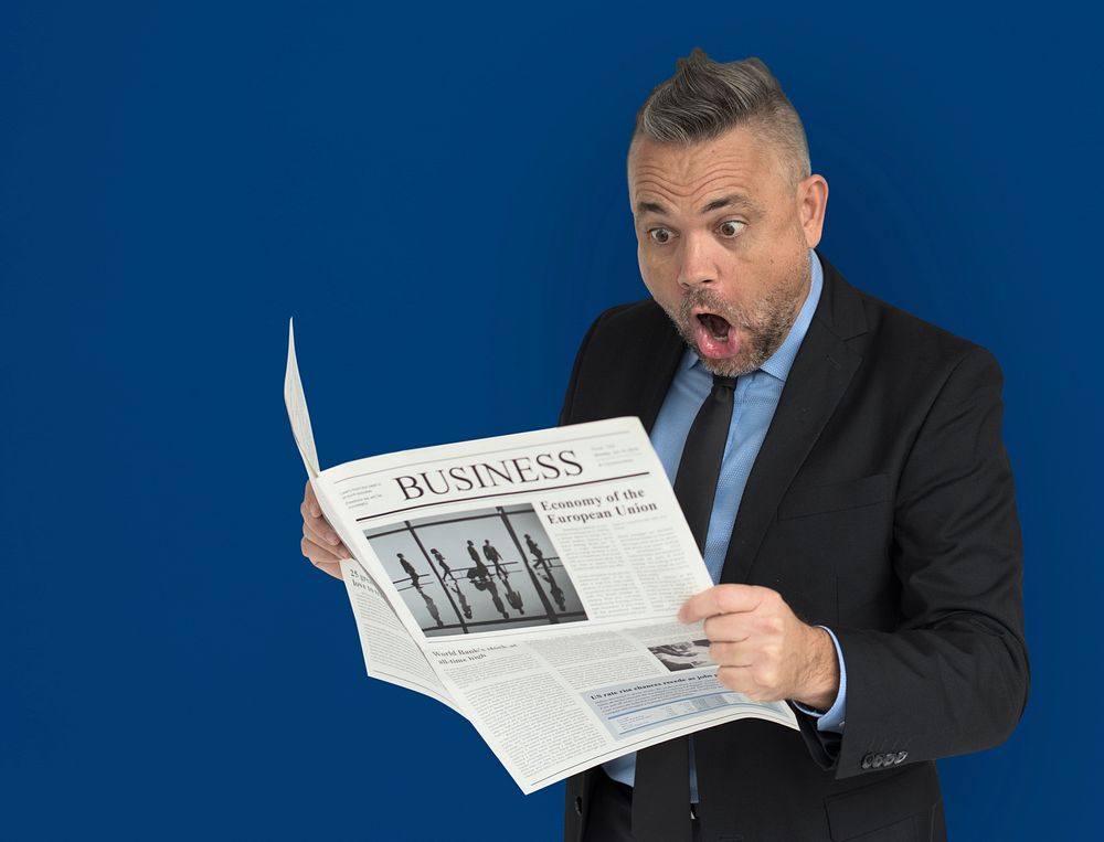 Caucasian Business Man Reading Newspaper Shocked