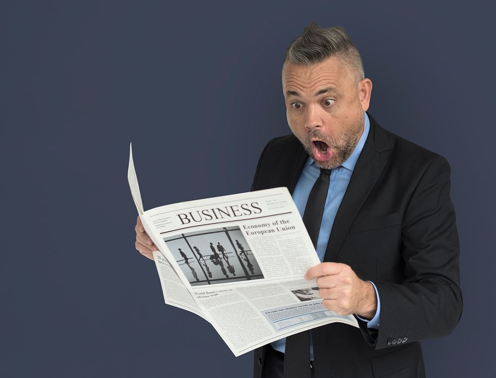 Caucasian Business Man Reading Newspaper Shocked