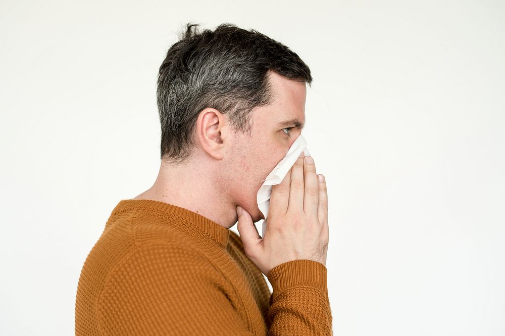 Portrait of a mature man sneezing into tissue