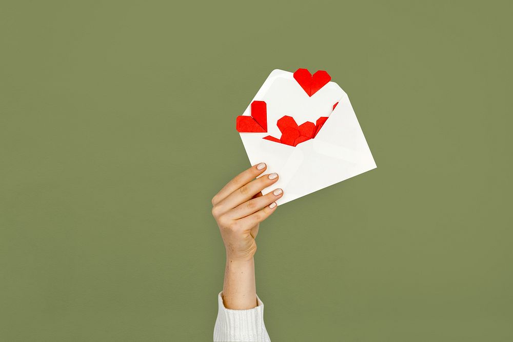 Hand holding envelope red paper hearts