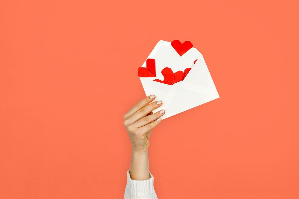 Hand holding envelope red paper hearts