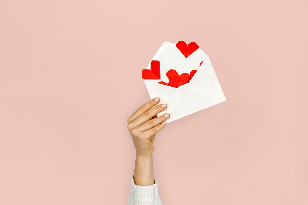 Hand holding envelope red paper hearts
