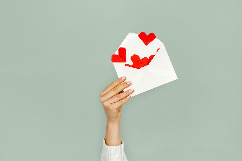 Hand holding envelope red paper hearts