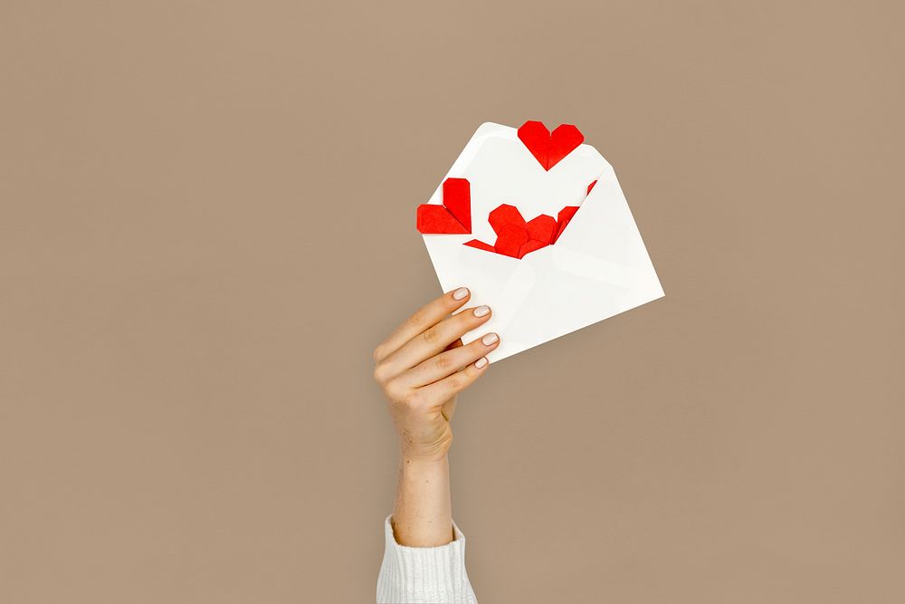 Hand holding envelope red paper hearts