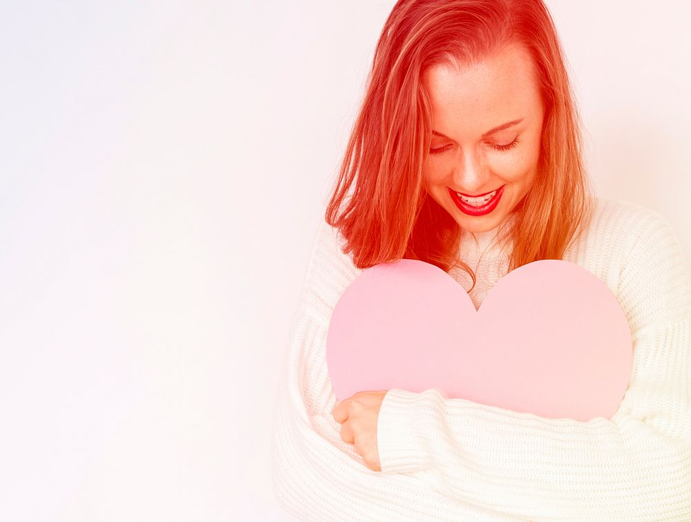 A caucasian woman is smiling holding heart.