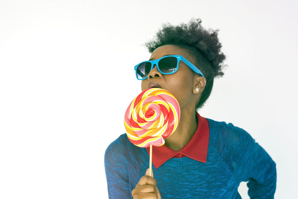 African hipster woman eating lollipop on white background