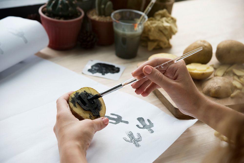Woman Painting Potatoes On Wooden Desk