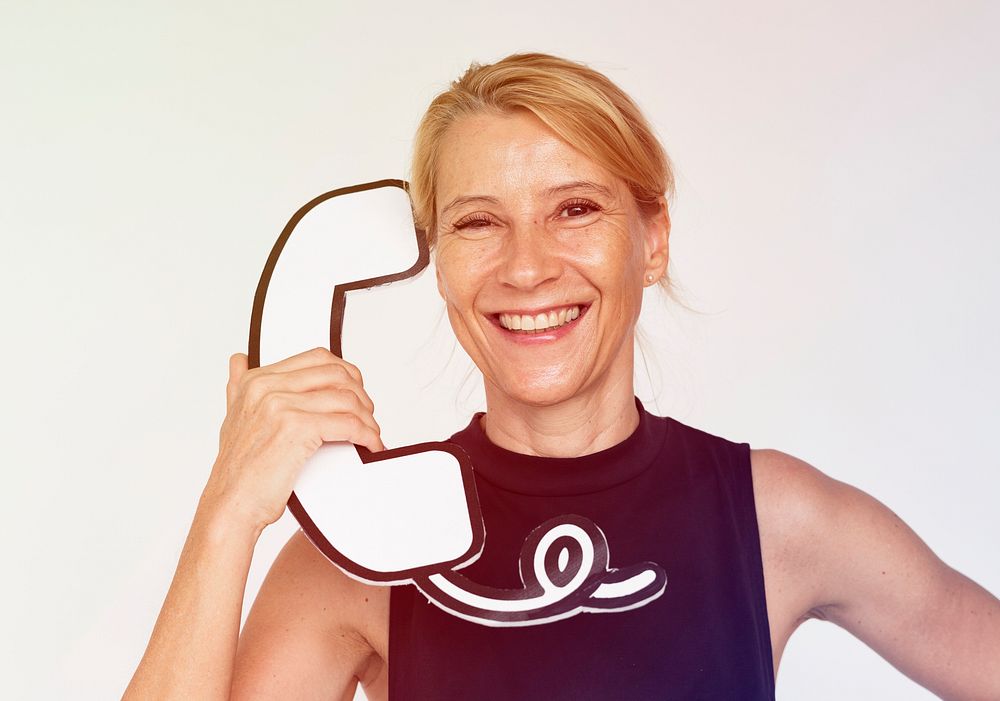 Woman holding papercraft telephone and smiling