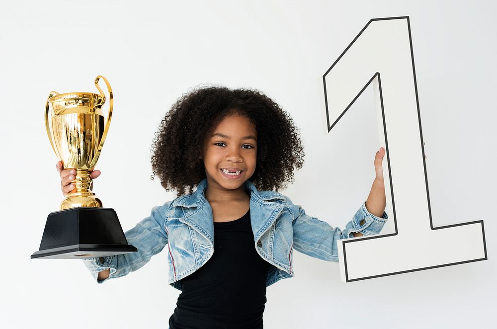 Studio portrait of a young girl with a trophy and number one