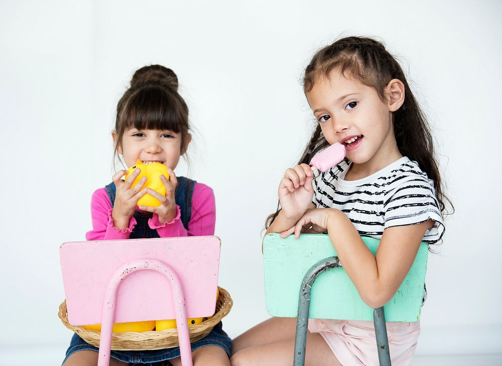 Elementary Age Schoolgirls Sitting on the Chair on the White Background
