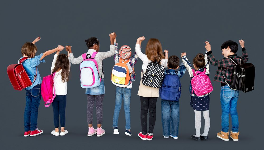 Rear view group of diverse kids standing in a row holdings hands in the air