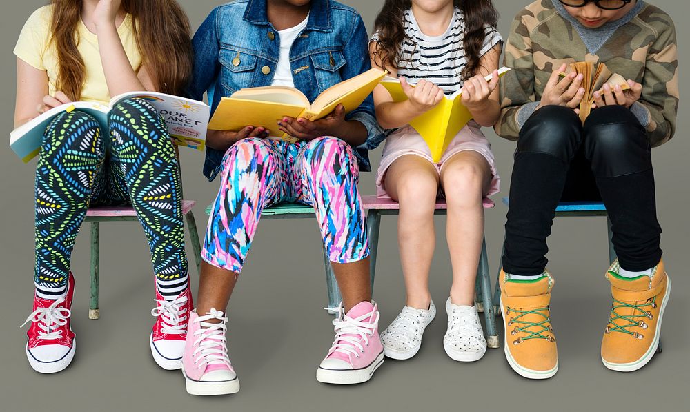 Diverse group of kids sitting in a row reading books