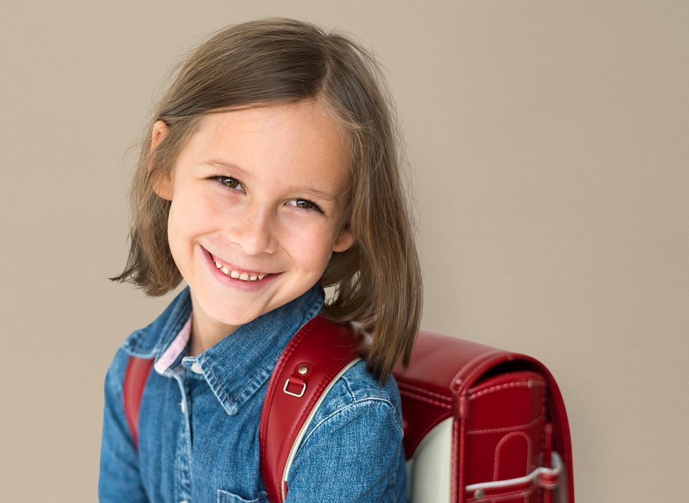 Young girl with a backpack cheerful studio portrait